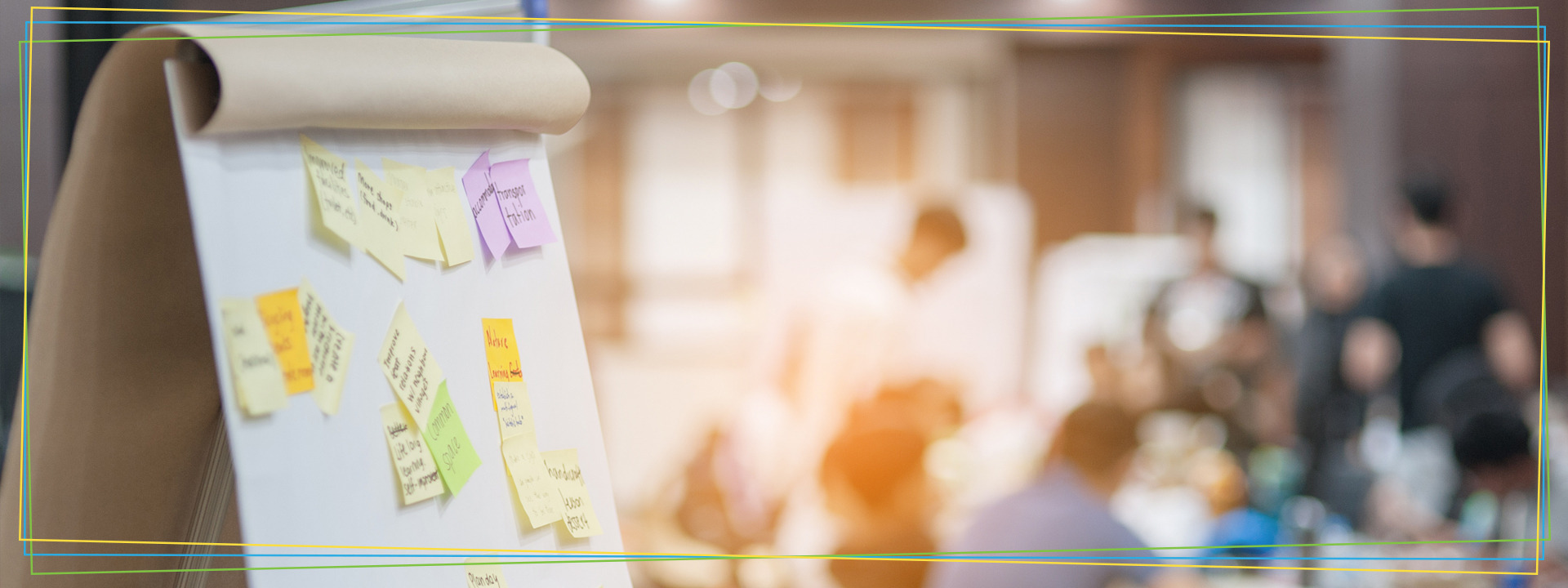 colorful sticky notes on an easel with a group of people collaborating in the background